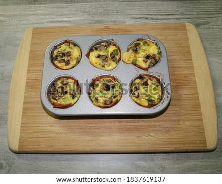 Egg muffins inside muffin tins with turkey bacon, mushrooms and green peppers.