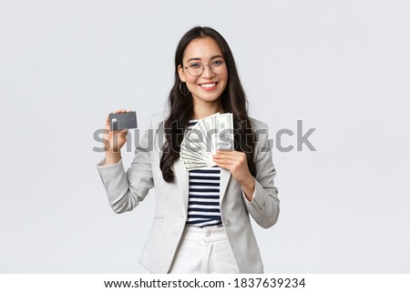 Business, finance and employment, entrepreneur and money concept. Successful asian businesswoman showing how increase income, hold credit card and money, smiling camera