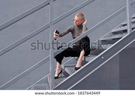 Smart attractive woman with short hair. A businesswoman using her smartphone and smiles on a city street.