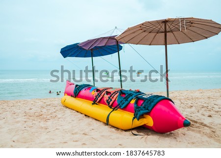 banana boat and life jacket lays on the beach under umbrella.