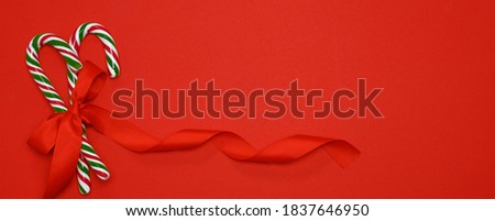 Two Candy Canes with a tied bow. Red background.banner. High quality photo