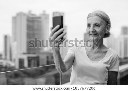Beautiful senior woman with blond hair against view of the city