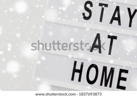 medicine, epidemic and healthcare concept - lightbox with stay at home caution words on white background in winter over snow