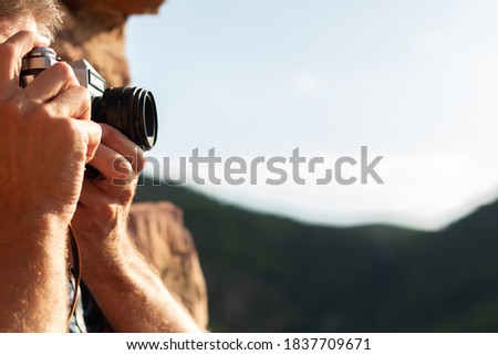 Side view of a man's hands taking a picture with a vintage camera at sunset. Photography concept