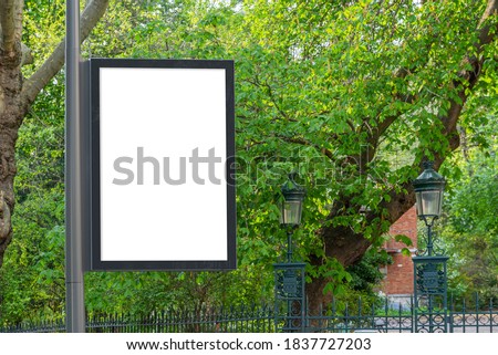 Billboard Mockup in a city with natural landscape. Parisian style hoarding advertisement on a pole close to a park with green trees