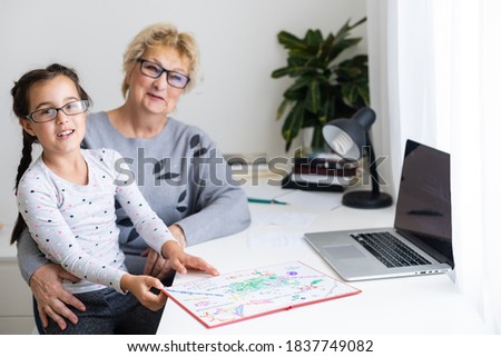 Helpful granny. Helpful loving granny assisting her cute granddaughter making homework