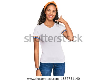 Young african american girl wearing casual clothes smiling doing phone gesture with hand and fingers like talking on the telephone. communicating concepts. 