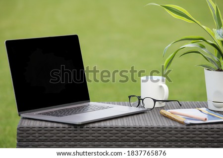 Working place with laptop, notebook, cup, glasses and flower on green background. Freelancer working place. copy space