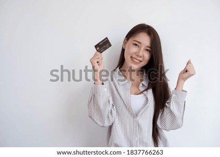 Portrait of a beautiful and cute Asian woman smiling and standing with a credit card on a white background, copy space.