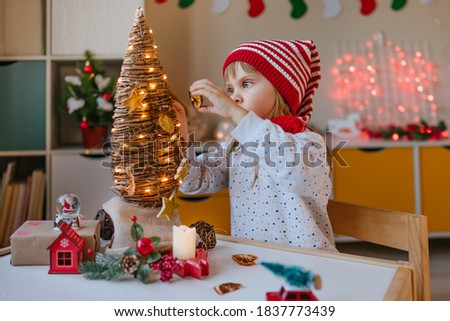 Little girl decorated Christmas eco tree indoor