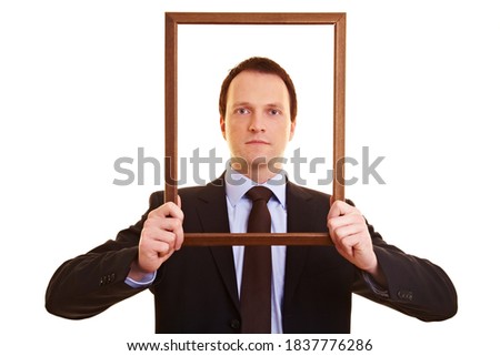 Businessman looking through an empty wooden frame