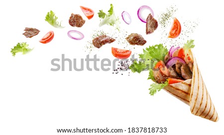 Doner kebab or shawarma with ingredients floating in the air: beef meat, lettuce, onion, tomatos, spice. White background. Copy space. Royalty-Free Stock Photo #1837818733