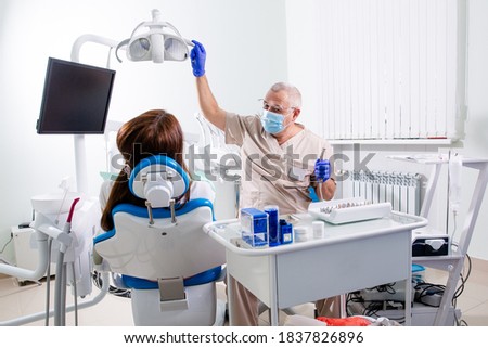 Dentist treats teeth of a patient sitting in a chair in a dental clinic