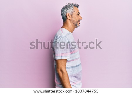 Middle age grey-haired man wearing casual clothes looking to side, relax profile pose with natural face with confident smile. 