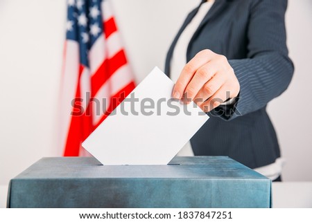 Close-up of voter putting ballot into voting box.