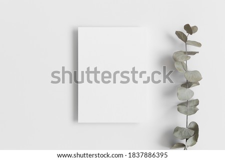 White invitation card mockup with a eucalyptus branch. 5x7 ratio, similar to A6, A5. Royalty-Free Stock Photo #1837886395