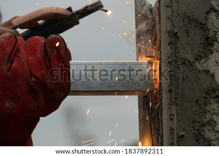 Construction worker : Welding of steel on the cement wall of angle iron rod. With sparks coming out of welding