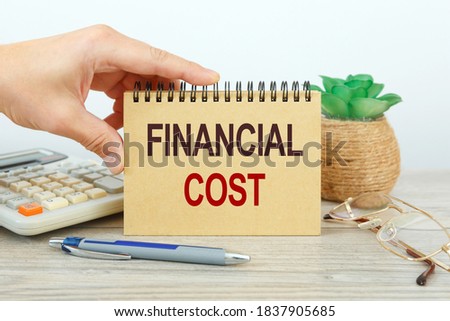 Business concept - workspace office desk and notebook writing FINANCIAL COST