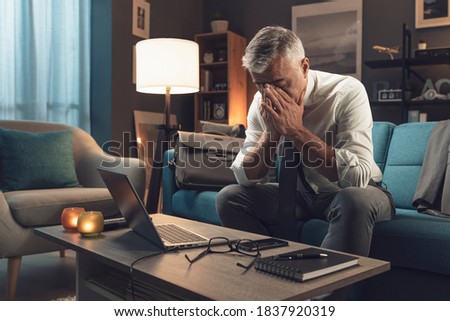 Exhausted businessman resting on the sofa at home after working all day long, stress and overwork concept Royalty-Free Stock Photo #1837920319
