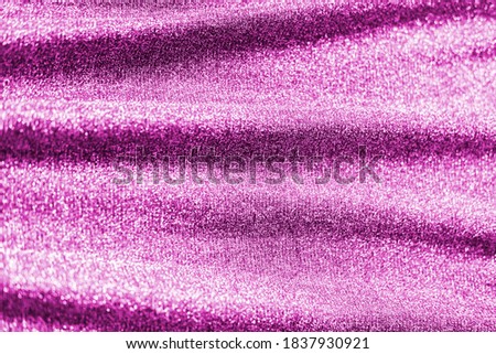 Colored raspberry pink magenta shiny fabric texture with folds. Surface background colors of the year 2021.
