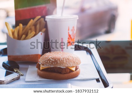 Hamburger, french fries, drink on tray standing from fastfood restaurant with key and smartphone