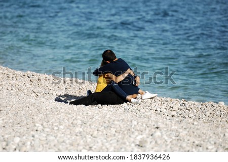 A love couple sits tight embraced on the beach of Altea-Spain.