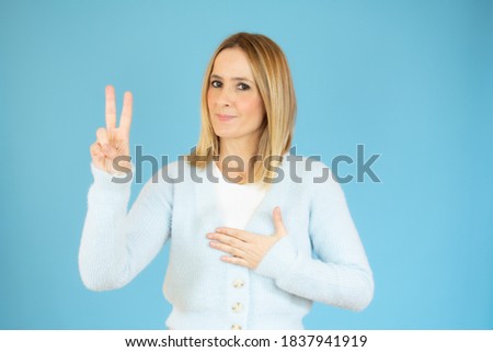 Beautiful young woman happy and excited expressing winning gesture. Successful pretty woman celebrating victory, triumphant, studio shot over blue background