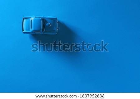 Top view of a Blue toy car on a blue background with long and side shadow.
