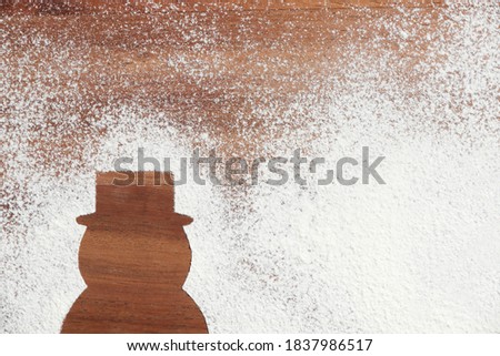 Silhouette of a traditional minimalist Christmas snowman wearing a hat, wood and snow, copy space