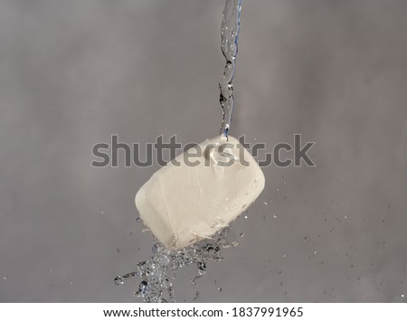 Stream of water breaks into a bar of soap.