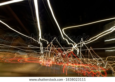 Long exposure light trails as abstract urban background. Different light trails of multicolored street lanterns and passing cars scattering in the dark, long exposure urban abstract background.