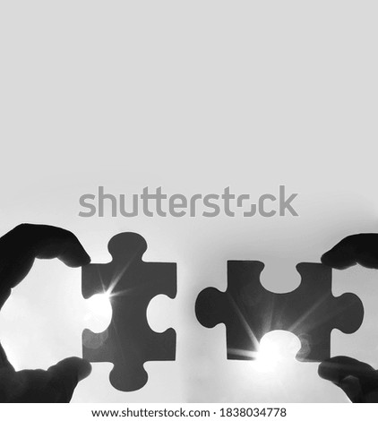 two hands of businessman to connect couple puzzle piece with sky background.Jigsaw alone wooden puzzle against sun rays.one part of whole.symbol of association and connection.business strategy.
