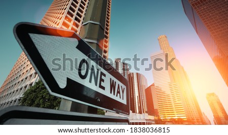 Sunrise over city skyline. Direction road sign "One Way" in financial district of downtown Los Angeles.
