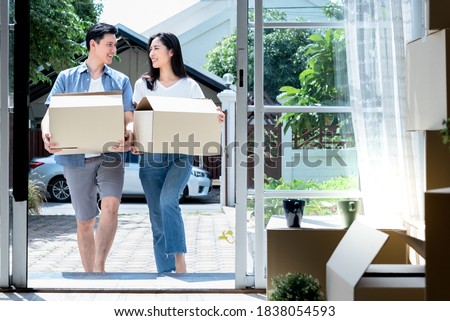 Asian couple, husband and attractive wife helping each other to lift the box Happily, to move into a new home For starting a marriage and family life.