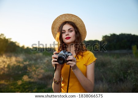 Woman in a hat with a camera in her hands red lips attractive look nature