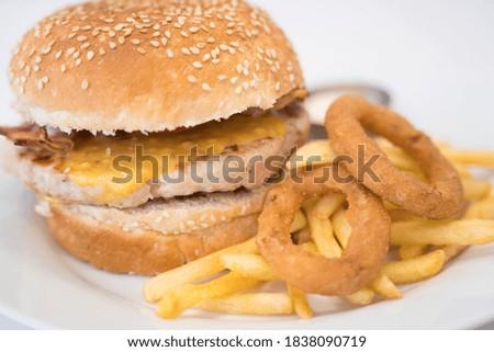 Homemade cheeseburger, fries, and onion rings on a plate