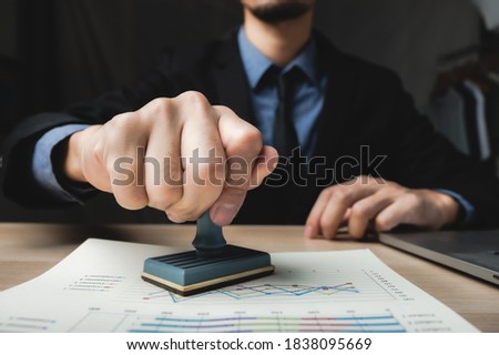person's hand stamping with approved stamp on business marketing document at desk in modern office