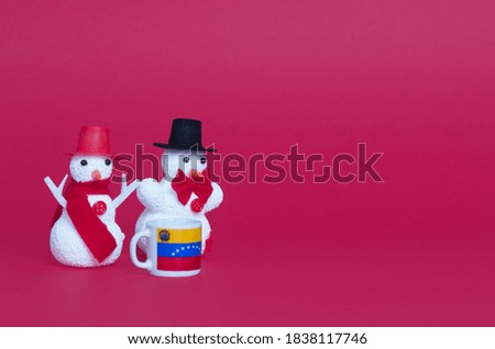 christmas snowmen on colored background and mug with venezuela flag