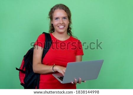 Beautiful german female student working at computer isolated on green background