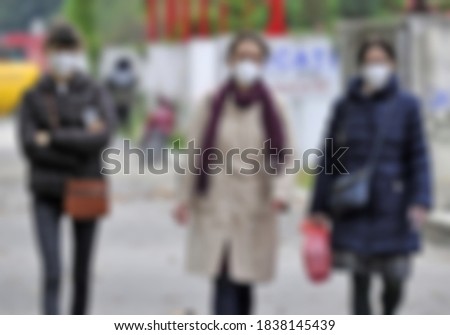 Blurred image of women with masks walking on the street