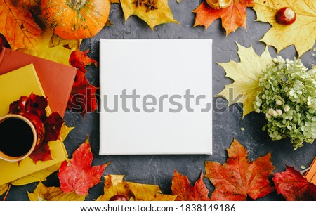 Blank canvas and autumn background. Mockup poster, autumn leaves, pumpkin and books with coffee cup.