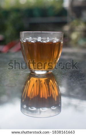 Image of a glass tumbler and it's reflection makes it look like an hourglass or sandwich . Selective focus on the glass and background is blurry 