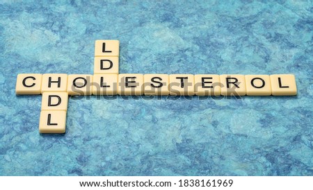 hdl and ldl  cholesterol crossword in ivory letter tiles against textured handmade bark paper, health and medical concept