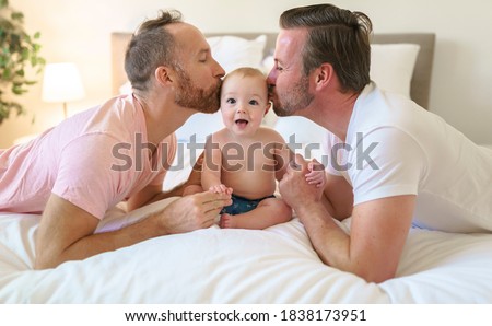 Male gay parents relaxing in bed with baby Royalty-Free Stock Photo #1838173951