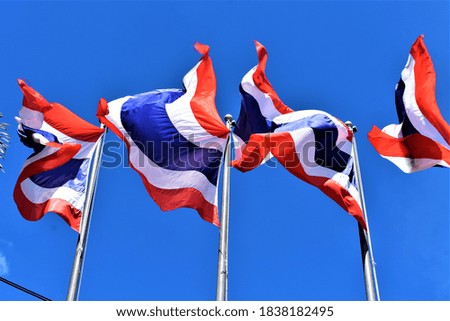 Thai​ national​ flag​ blowing​ in​ bright​ sunlight​ blue​ sky​ background