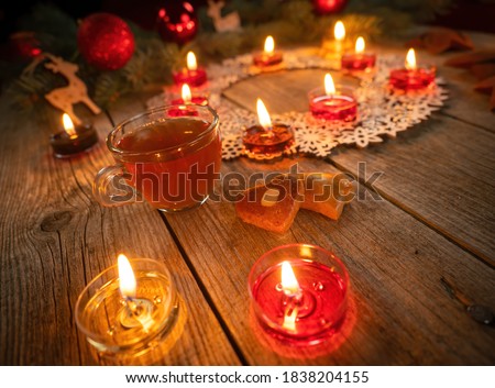 Winter ornamental decoration with burning candles on wooden rustic table. Mulled wine punch with gingerbread in foreground. Christmas holidays and New Year theme. Close-up.