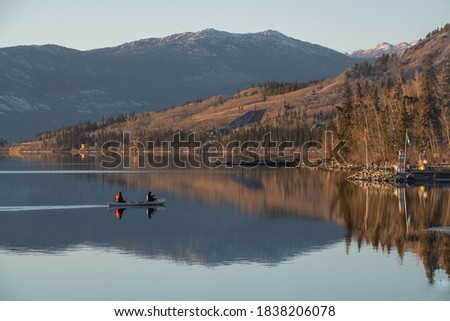 Two people canoing over a clear, calm and stunning lake surrounded by mountains and wilderness in Northern Canada. 