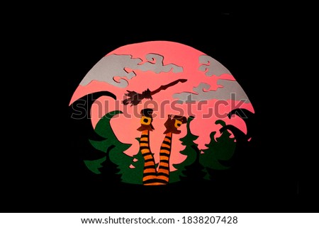 The legs of a witch on the background of the forest and the big red moon cut out of colored paper. Paper art photo for your spooky craft Halloween design. 