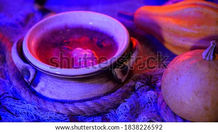 Witch is cooking potion in a gurgling cauldron. Halloween party decoration on a spooky background. Smoky bubbling witch cauldron with poison. 