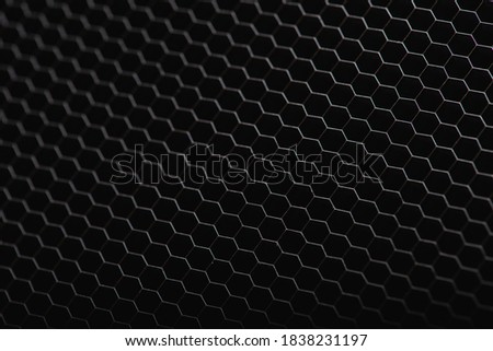 Panorama of black iron, plastic hexagonal texture. Industrial mesh background. Low key with selective focus